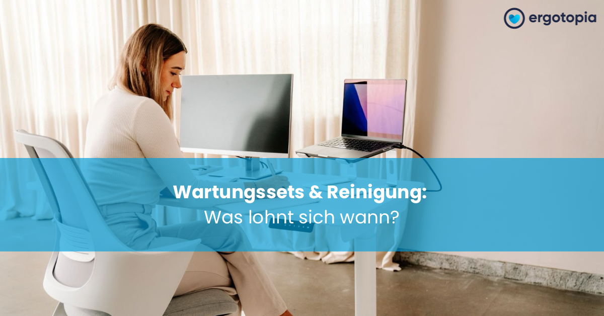 Frau schreibt am Schreibtisch, daneben Laptop auf silbernem Ständer neben externem Monitor.