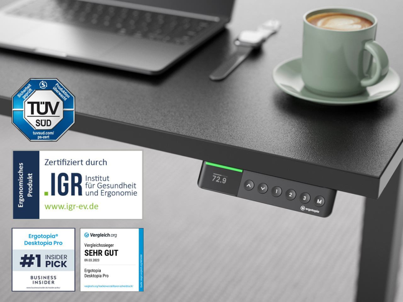 Detailbild eines schwarzen, ergonomisch zertifizierten höhenverstellbaren Schreibtischs (Ergotopia Desktopia Pro X) mit digitalem Bedienfeld und Trust-Siegeln von TÜV SÜD, IGR, Business Insider und Vergleich.org